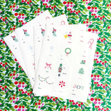 Five white Christmas-themed envelopes or cards fanned out on a green holly and berry patterned background. The white cards feature small festive illustrations including stockings, candy canes, ornaments, a nutcracker, wreath, bow, Christmas tree, and the word "JOY.
